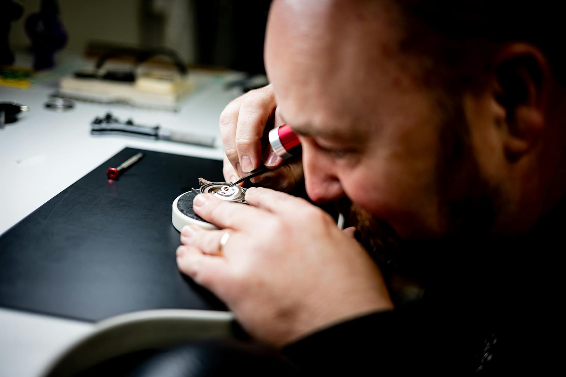 An attentive watchmaker examining and adjusting a watch mechanism with precision tools.