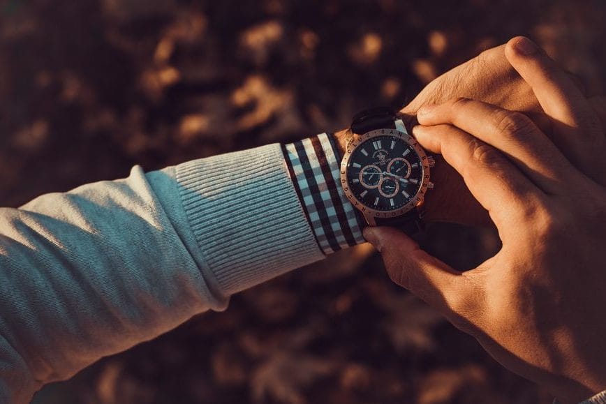 A slim gold dress watch on a leather strap worn under a suit cuff